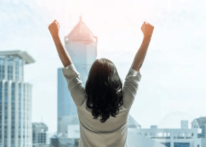 Person standing with arms raised in confidence, symbolizing resilience and leadership strength