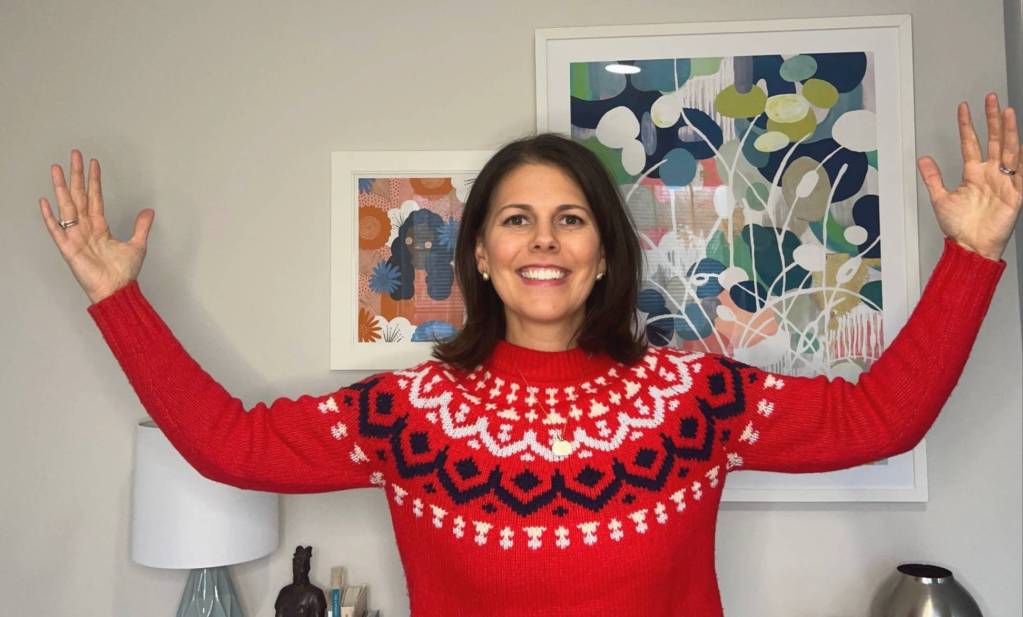 Smiling leadership coach with arms raised in celebration, reflecting on success and mindset